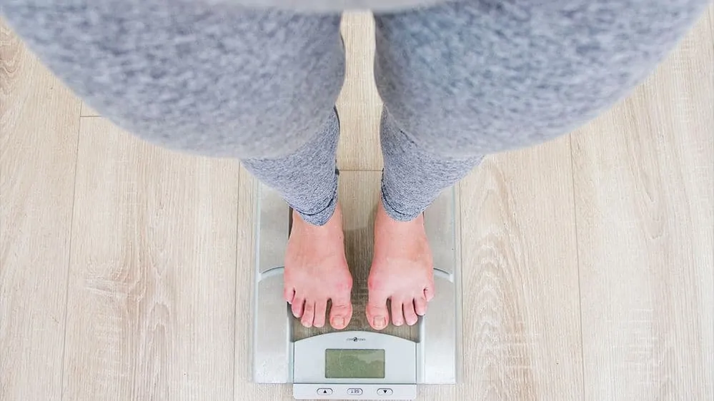 Woman weighing self on scale