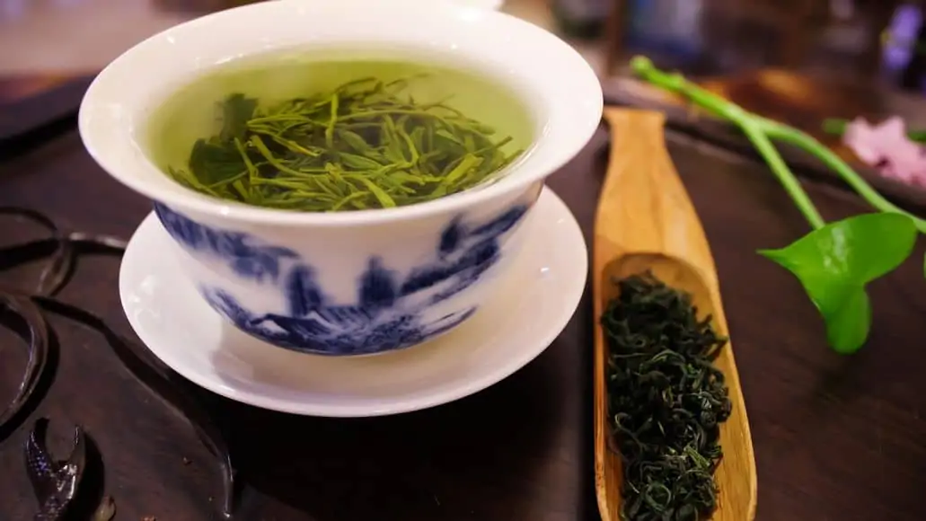 A cup of green tea with leaves